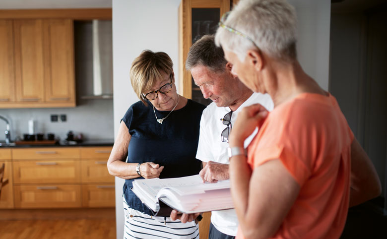 Karin Ek Hedle, Lucas Jönsson och Eva Kruse kikar igenom de papper som varje nyinflyttad får som introduktion till föreningen under det välkomnande som Brf Glasbruket alltid gör. Foto: Jenny Leyman