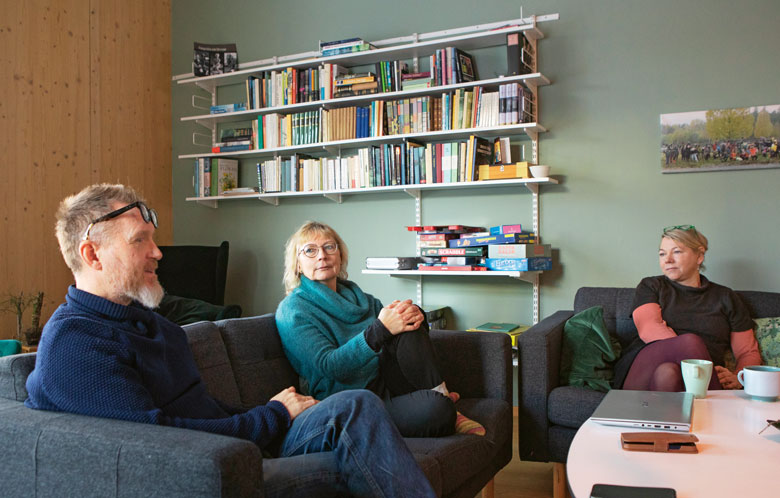 Grannarna Martin Wohlin, Ylva Liljeholm och Katja Jahn värmer sig framför brasan i föreningens gemensamma allrum. Foto: Andreas Renlund